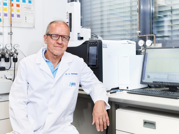 Ein Chemiker sitzt vor einem Gaschromatographen mit Massenspektrometer (GC-MS)